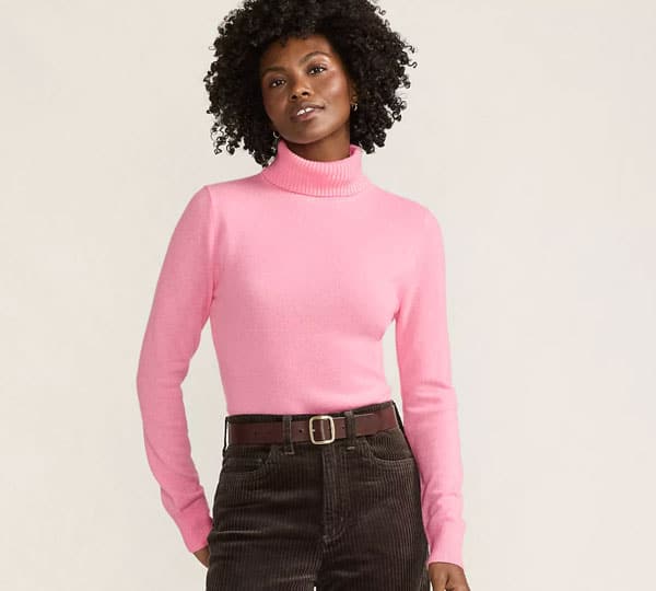 attractive woman in black jeans and pink turtleneck sweater